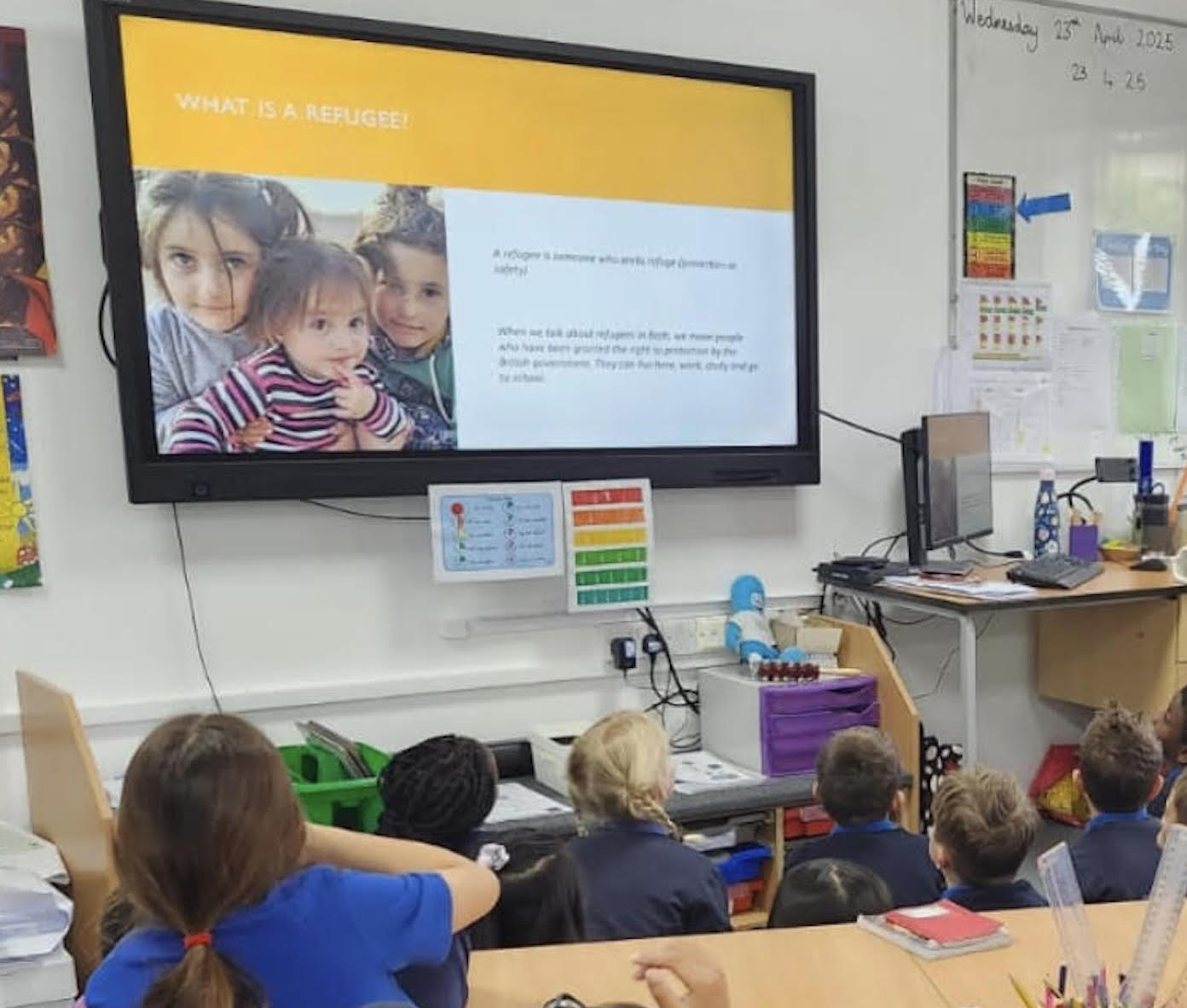 A presentation on a screen and the backs of people and children watching